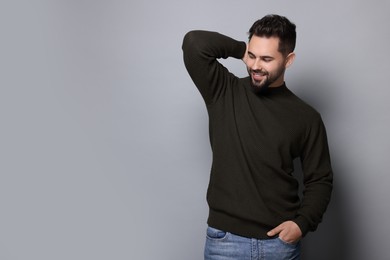 Happy man in stylish sweater on grey background, space for text
