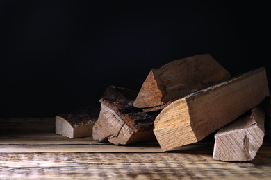 Cut firewood on table against black background