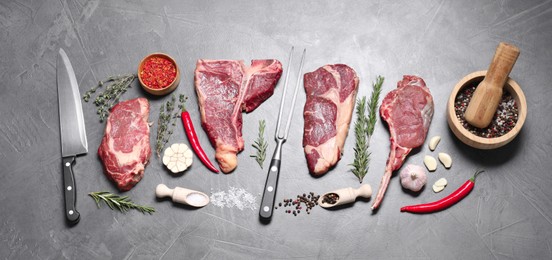 Photo of Fresh raw beef cuts, butcher tools and different spices on light grey textured table, flat lay