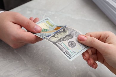 Photo of Woman giving money to man at light grey table, closeup. Currency exchange