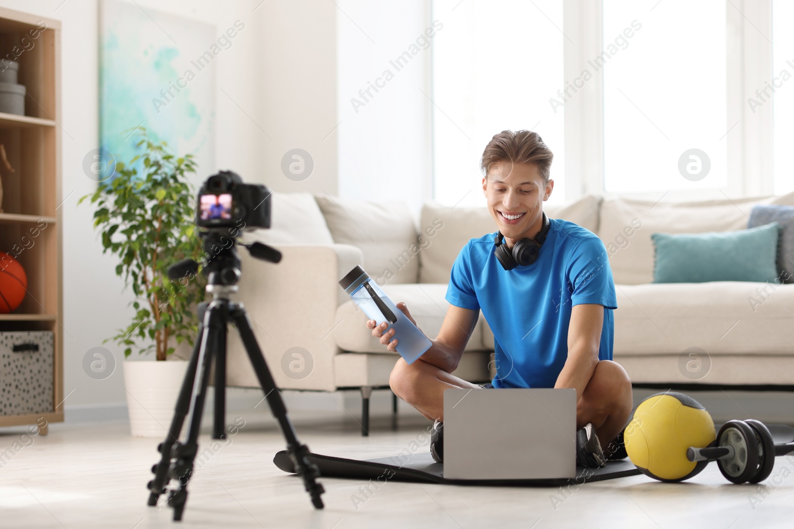 Photo of Smiling sports blogger recording fitness lesson with camera at home