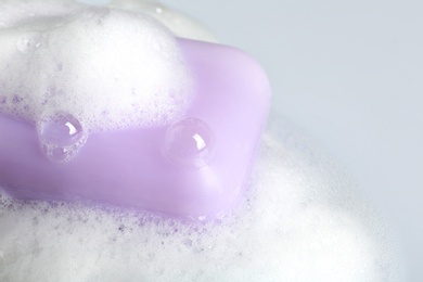 Photo of Soap bar and foam on light background, closeup