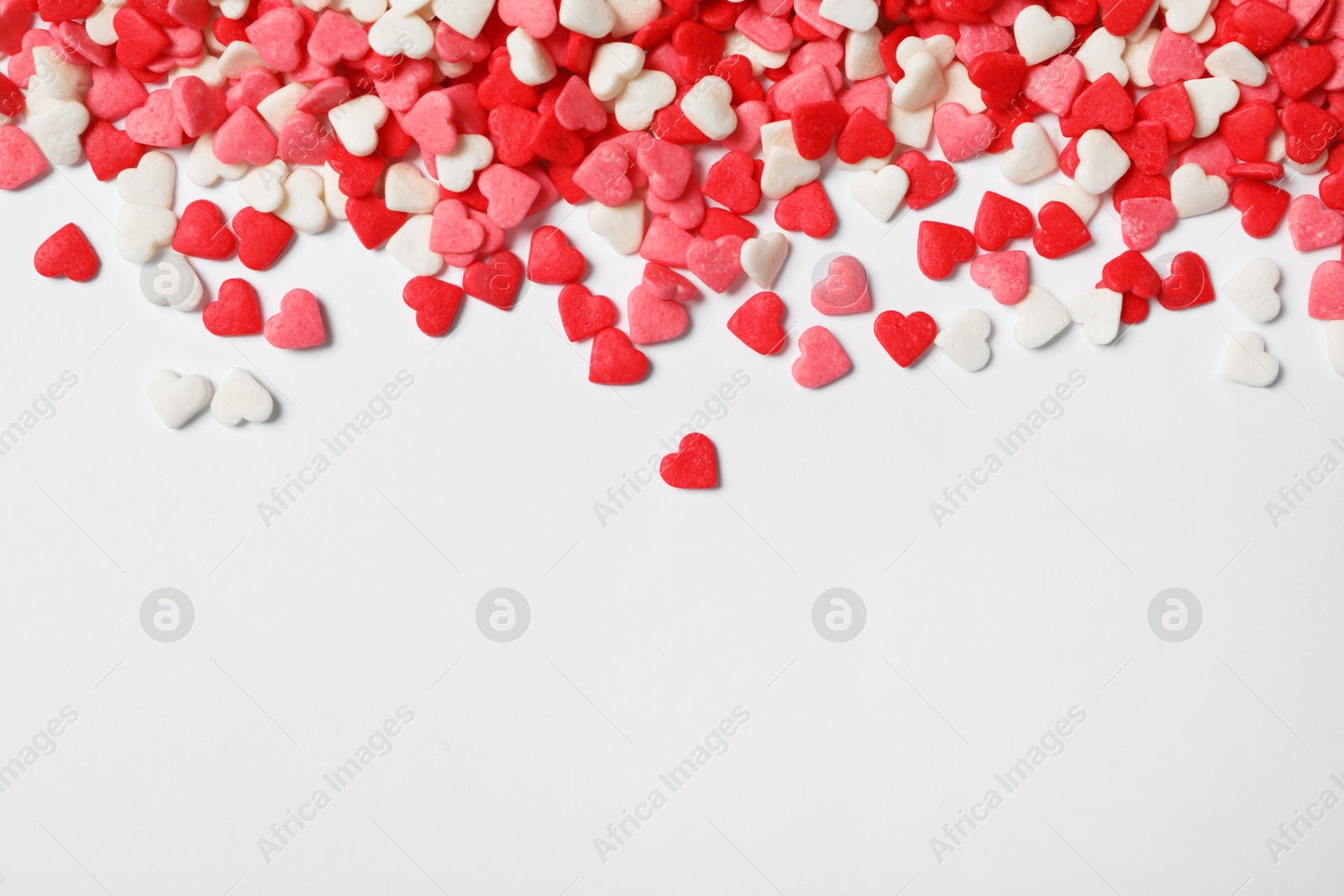 Photo of Bright heart shaped sprinkles on white background, view from above. Space for text
