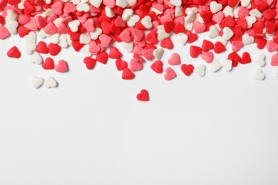 Bright heart shaped sprinkles on white background, view from above. Space for text