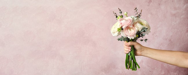 Woman holding bouquet with beautiful ranunculus flowers on pink background, space for text. Banner design