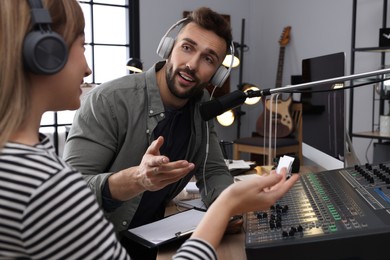 Photo of Man interviewing young woman in modern radio studio