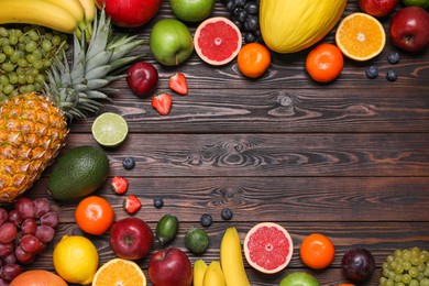 Photo of Different ripe fruits on wooden table, top view. Space for text