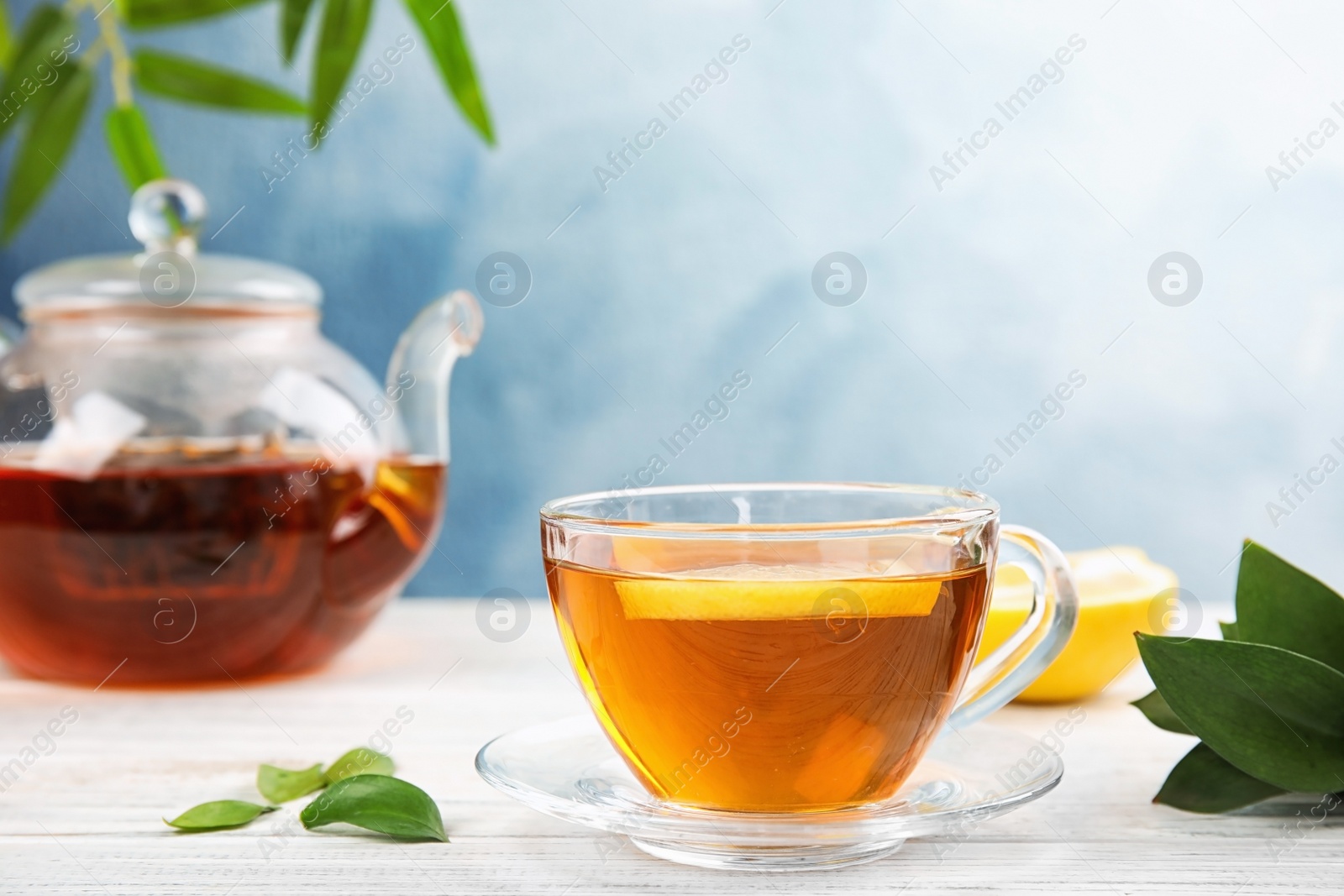 Photo of Glass cup and teapot with black tea on wooden table