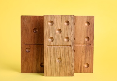 Photo of Wooden domino tiles with pips on yellow background