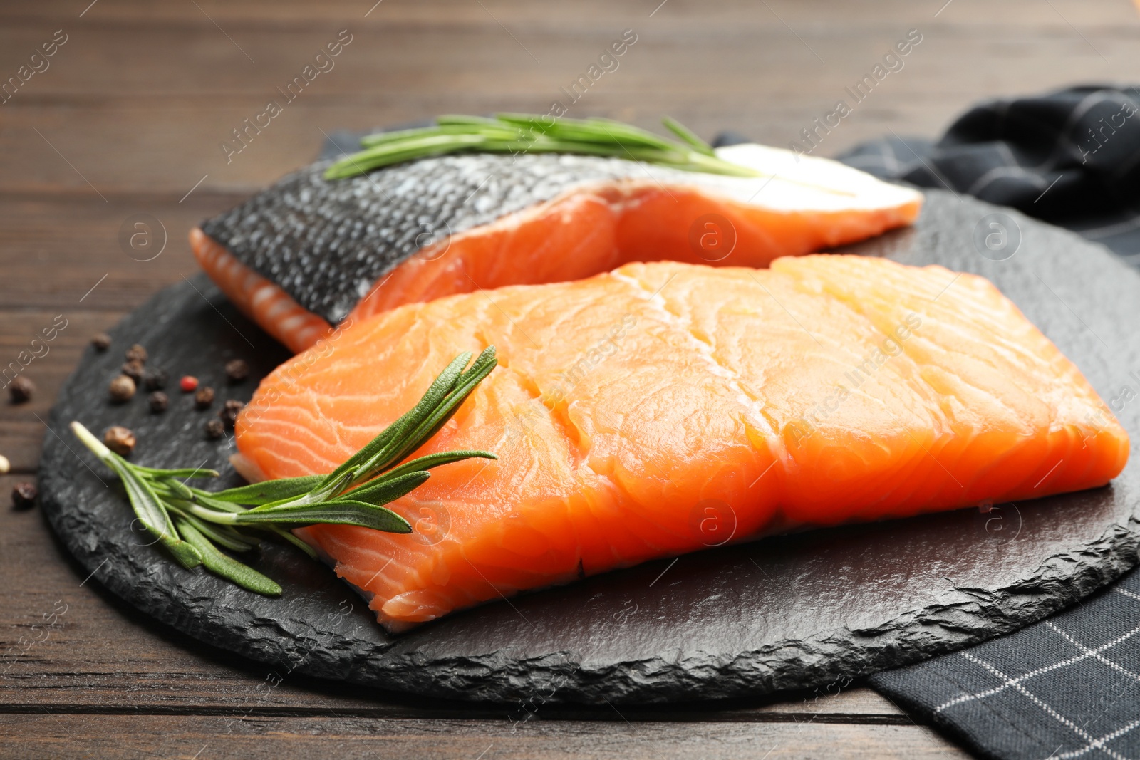 Photo of Slate plate with salmon fillet on table, closeup
