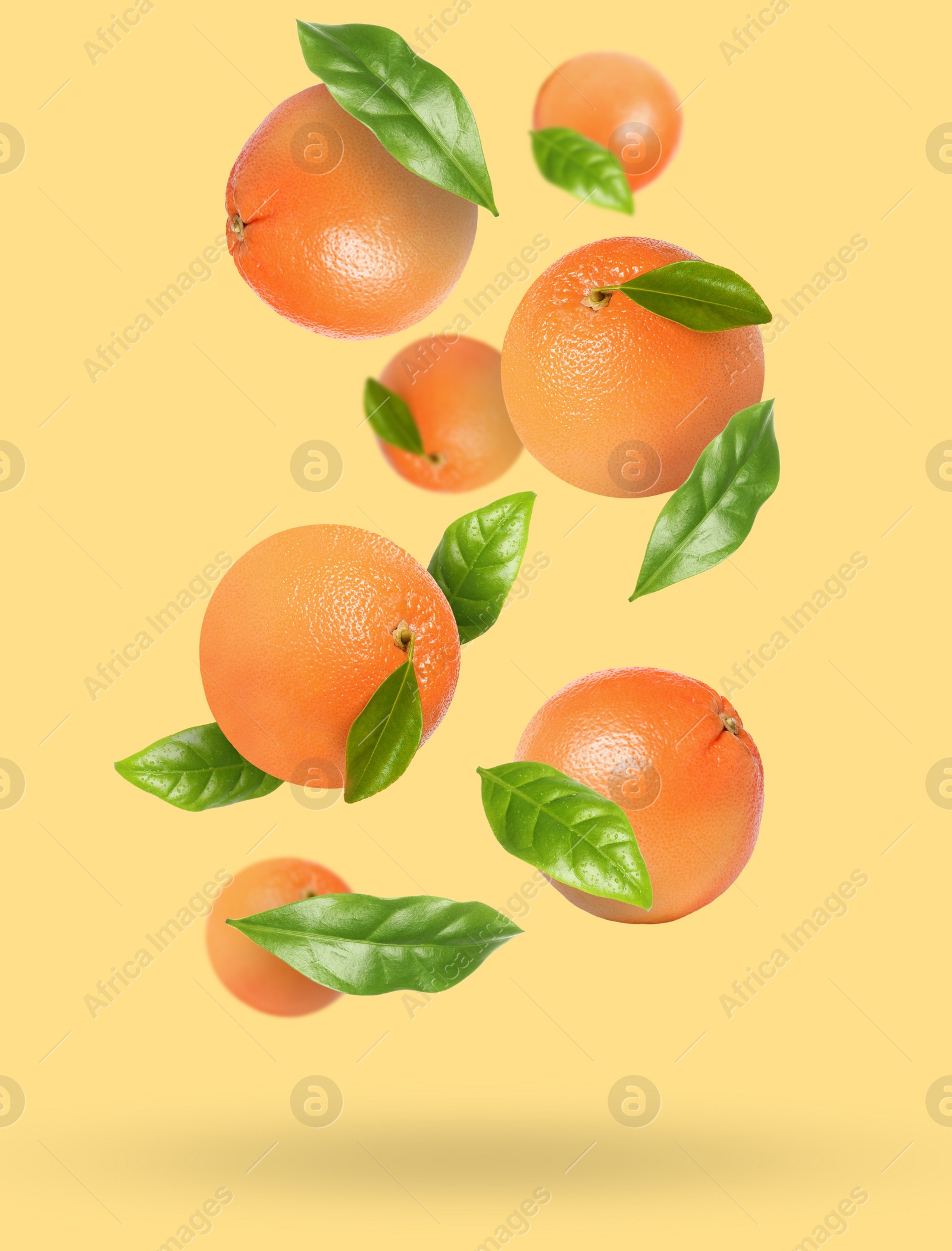 Image of Tasty ripe grapefruits and green leaves falling on beige background