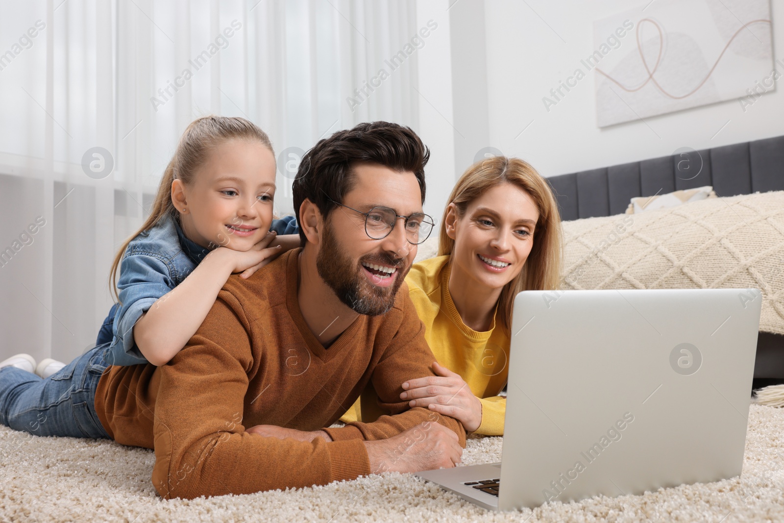 Photo of Happy family with laptop on floor at home