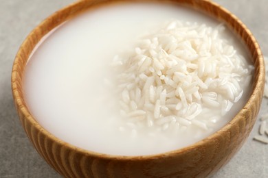 Rice soaked in water on light grey table, closeup