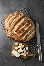 Photo of Freshly baked bread with tofu cheese and knife on black table, top view