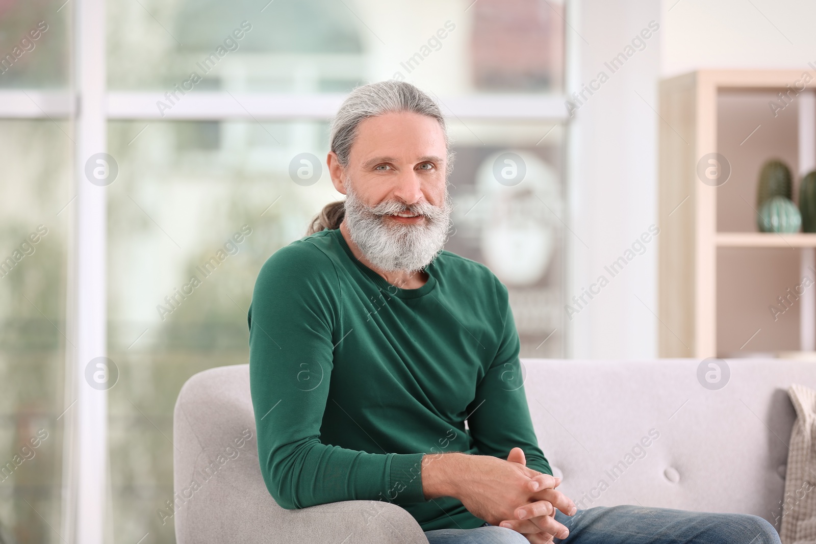 Photo of Portrait of handsome mature man on sofa, indoors