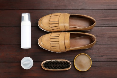 Photo of Flat lay composition with shoe care accessories and footwear on brown wooden background