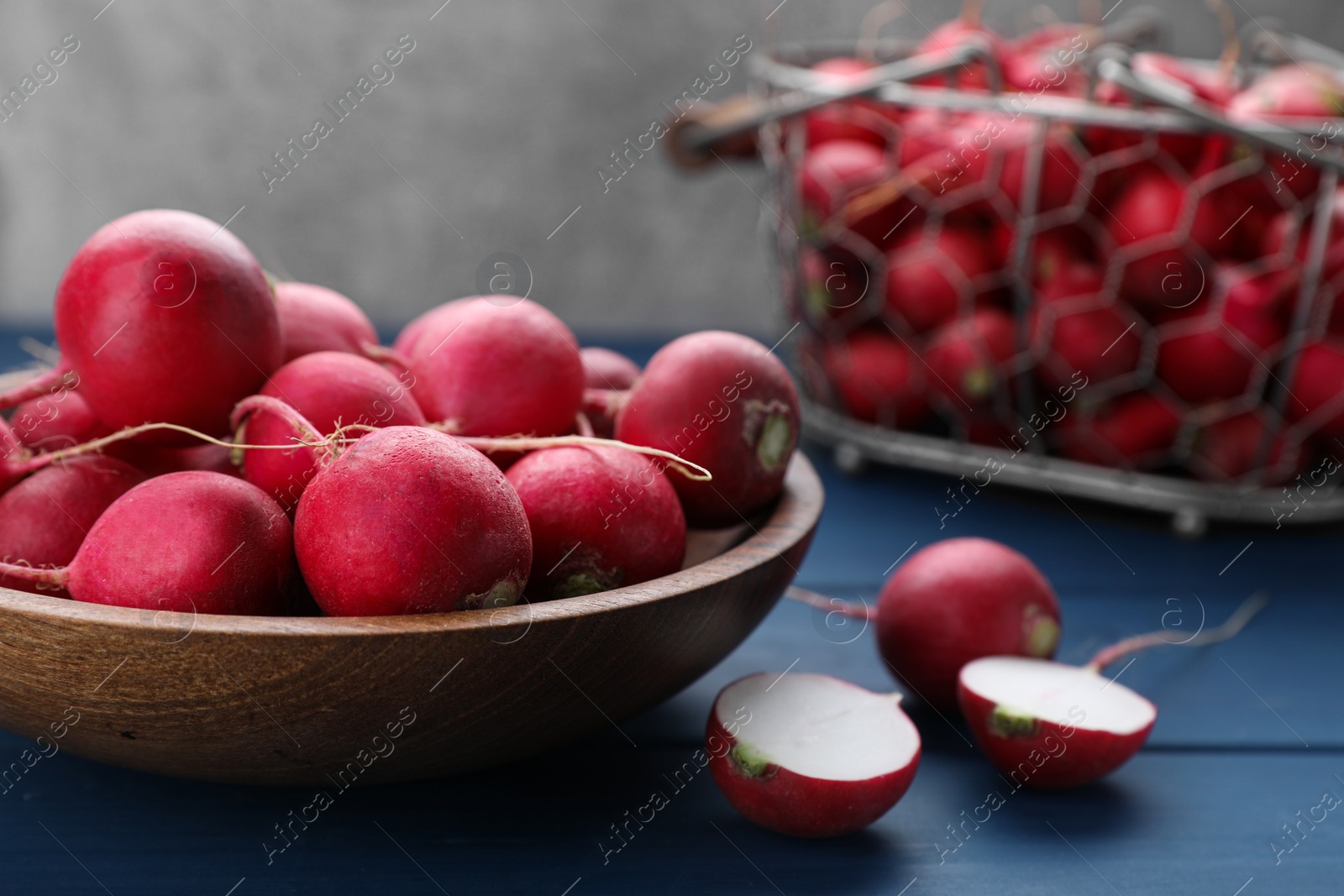 Photo of Bowl with fresh ripe radishes on blue wooden table, closeup