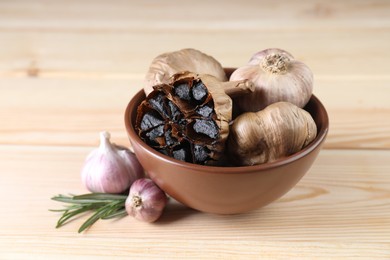 Photo of Bulbs of fresh and fermented black garlic on wooden table