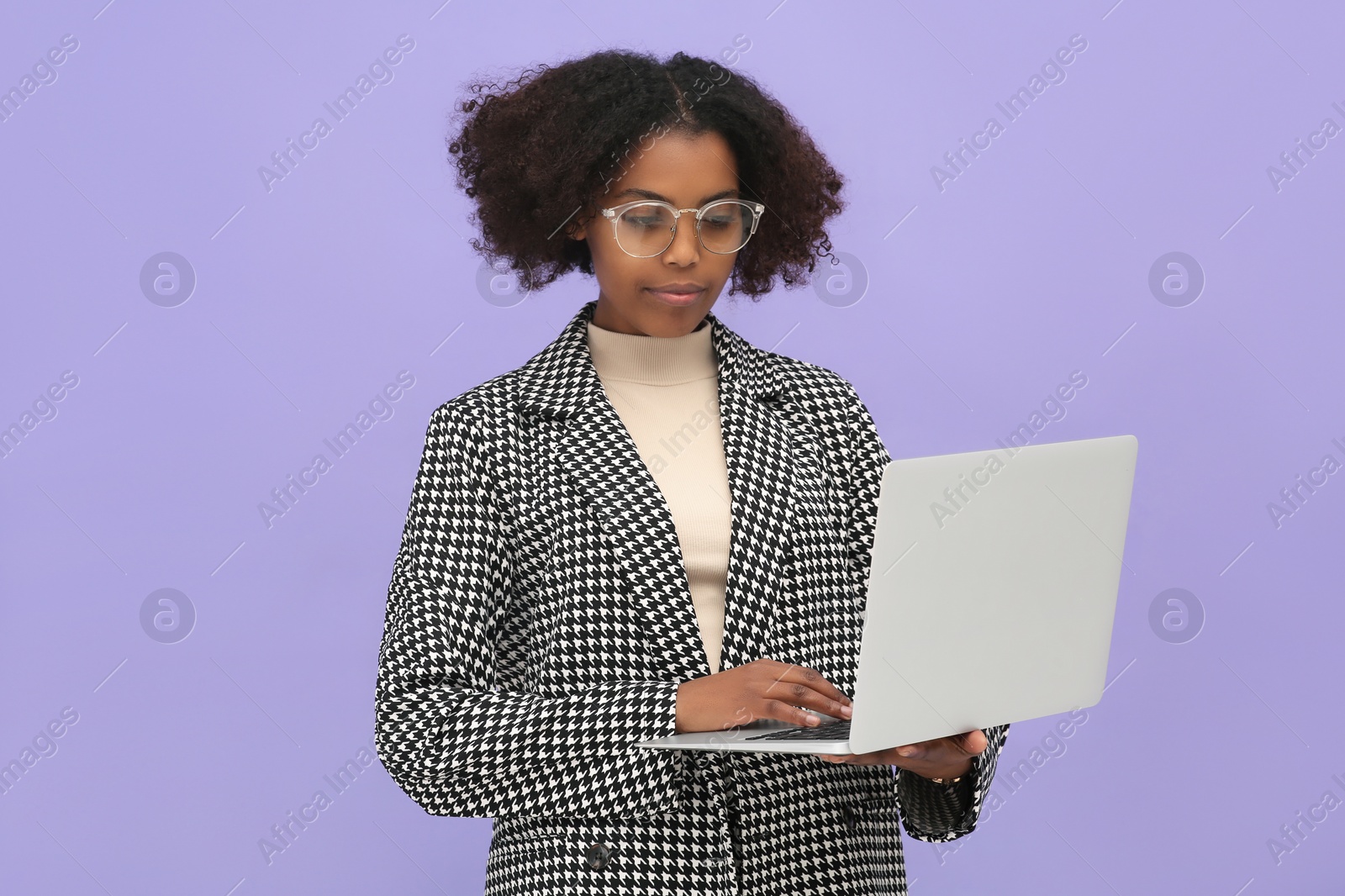 Photo of African American intern working on laptop against purple background