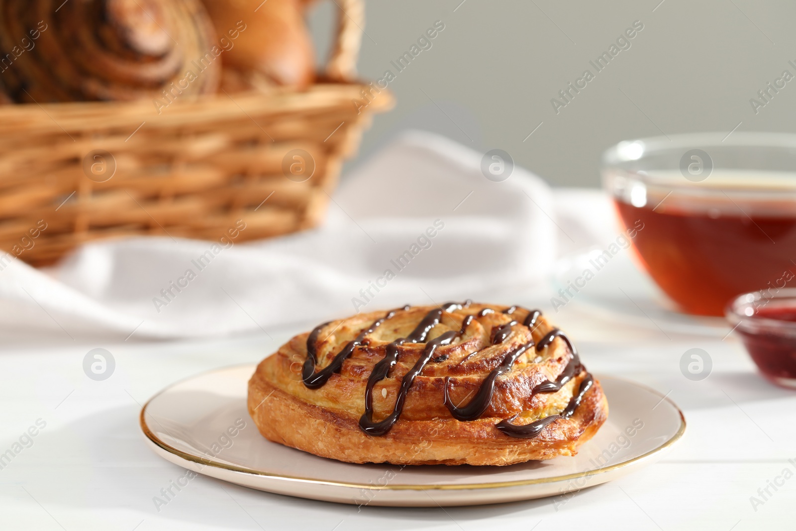 Photo of Tasty freshly baked spiral pastry on white table, closeup. Space for text