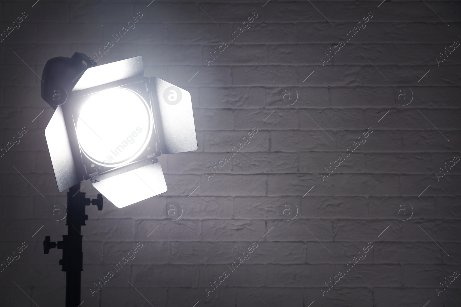 Photo of Professional photo studio lighting equipment near brick wall. Space for text