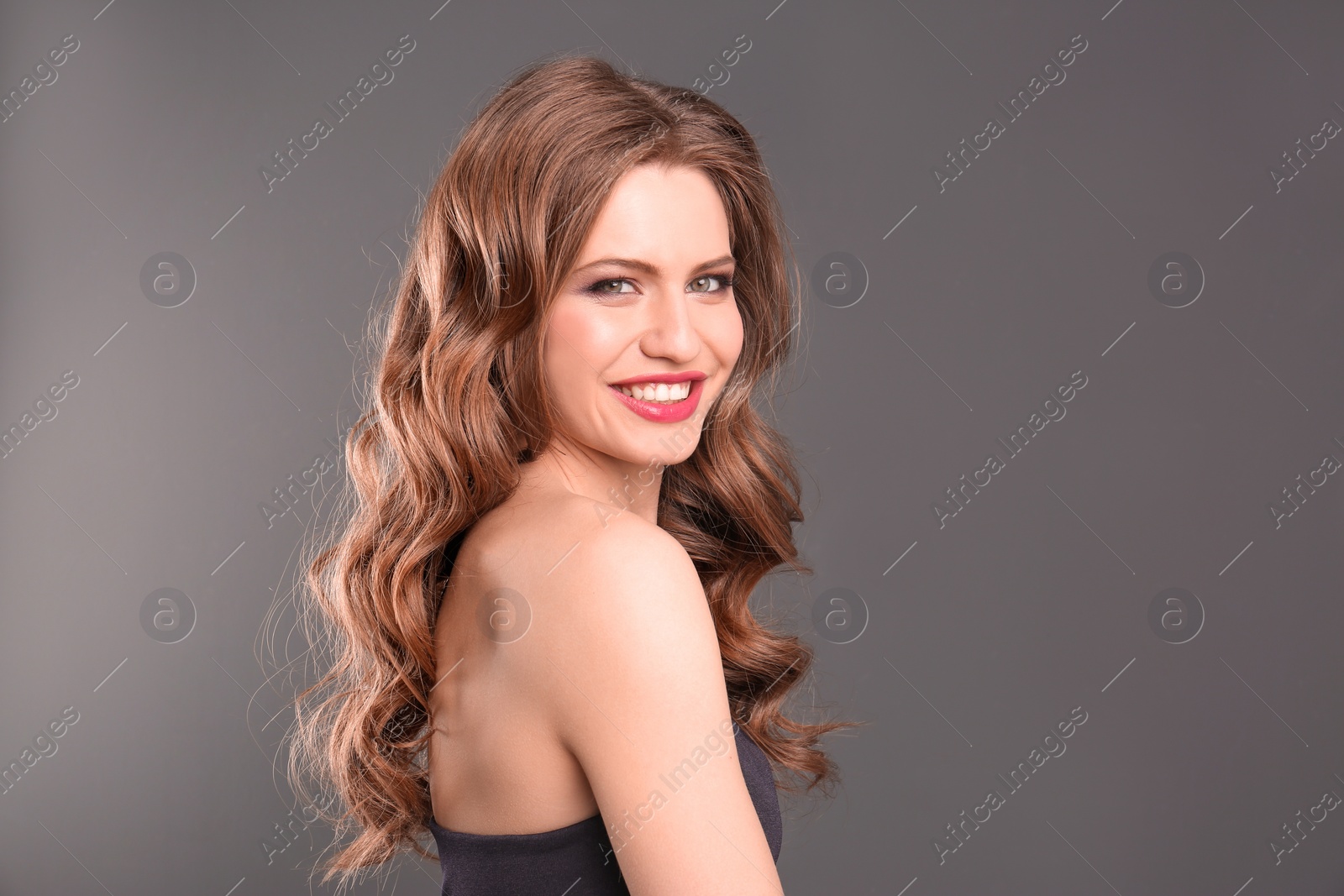 Photo of Portrait of young woman with long beautiful hair on grey background