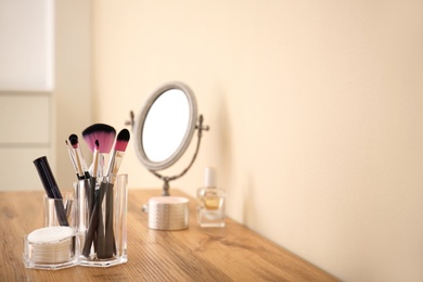 Photo of Makeup cosmetic products with tools in organizer on dressing table. Space for text