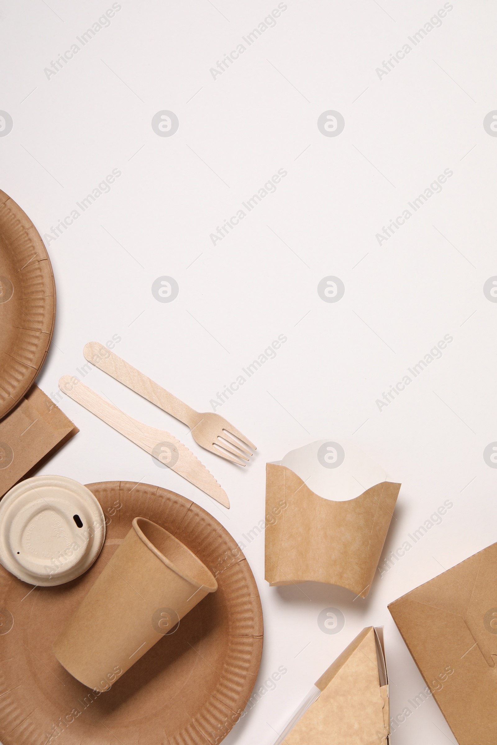 Photo of Eco friendly food packaging. Paper containers and tableware on white background, flat lay. Space for text