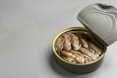 Photo of Open tin can of sprats on light grey table. Space for text