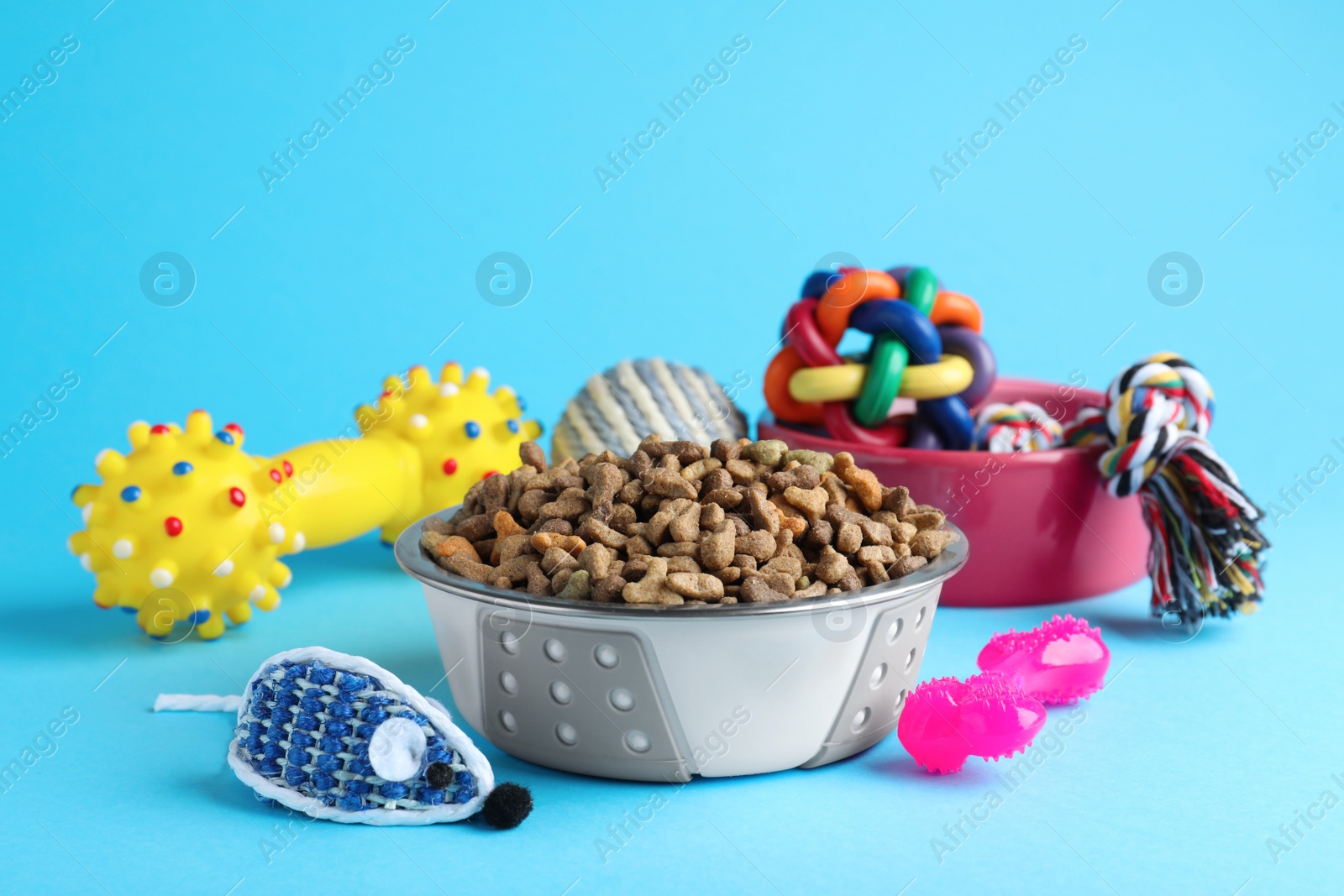 Photo of Feeding bowls and toys for pet on light blue  background