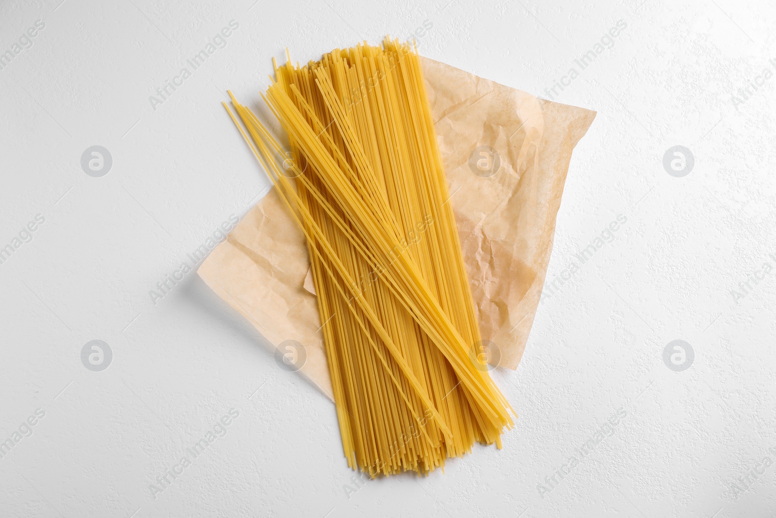 Photo of Uncooked spaghetti on white table, top view. Italian pasta