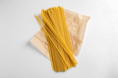 Photo of Uncooked spaghetti on white table, top view. Italian pasta