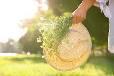 Photo of Young woman with straw hat and bouquet outdoors on sunny day, closeup