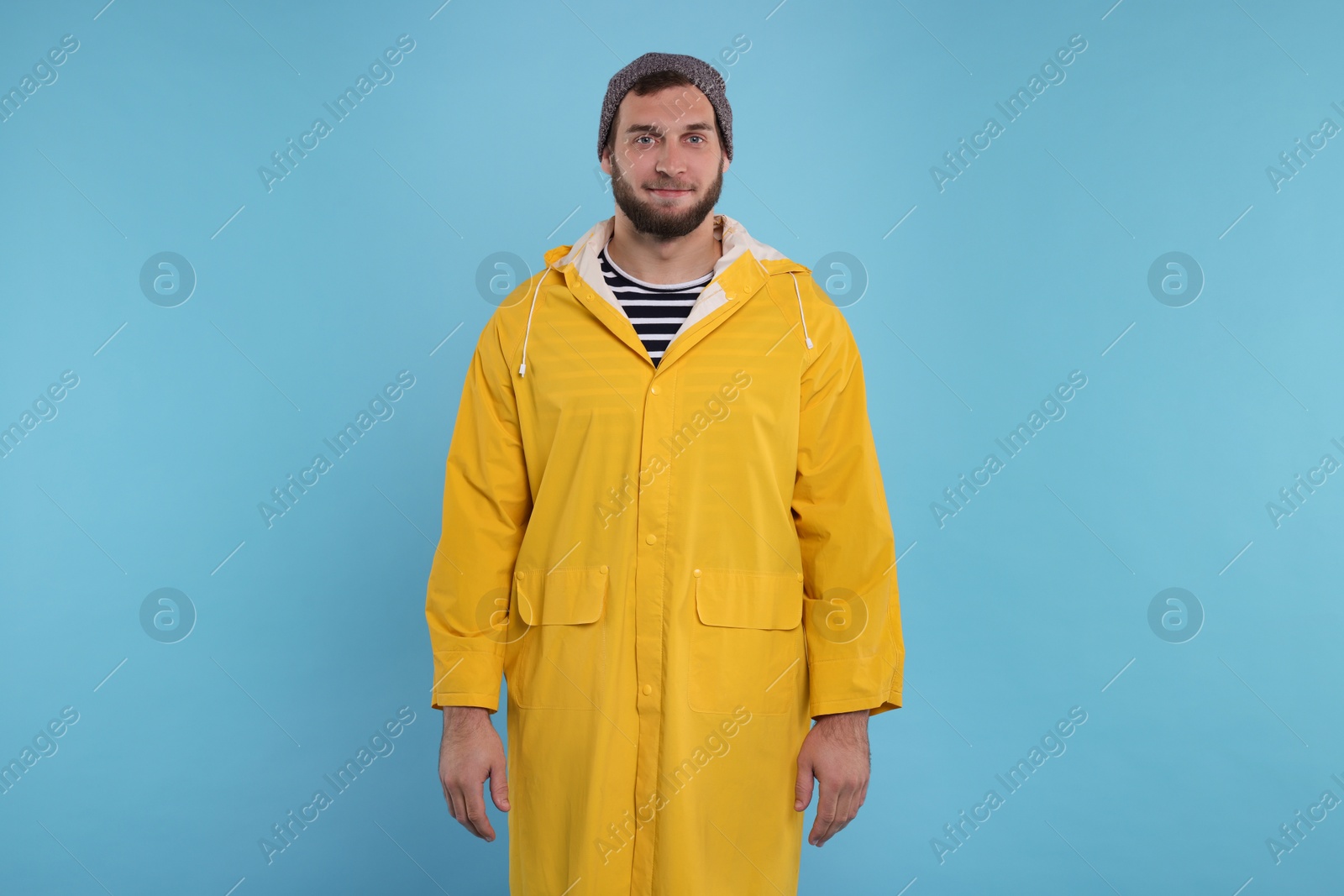 Photo of Fisherman in yellow raincoat on light blue background