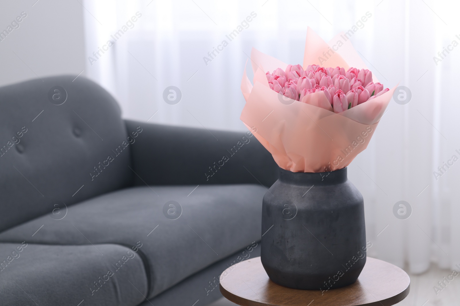 Photo of Bouquet of beautiful pink tulips in vase on wooden table indoors, space for text