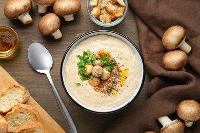 Photo of Delicious cream soup with mushrooms and ingredients on wooden table, flat lay