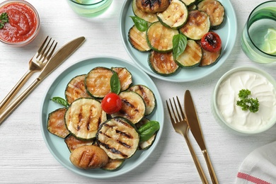 Photo of Flat lay composition with delicious grilled zucchini slices on white wooden table