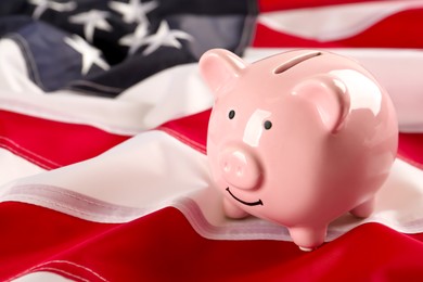 Photo of Pink piggy bank on American flag, space for text