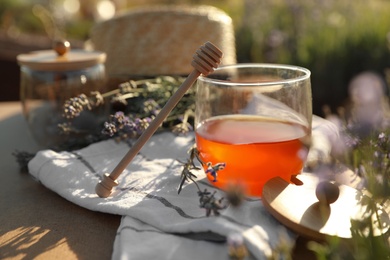 Jar of honey on wooden table in lavender field