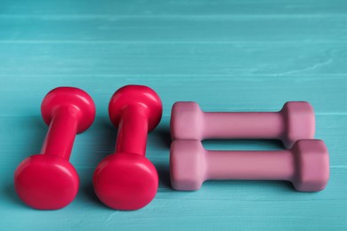 Photo of Set of pink dumbbells on turquoise wooden table