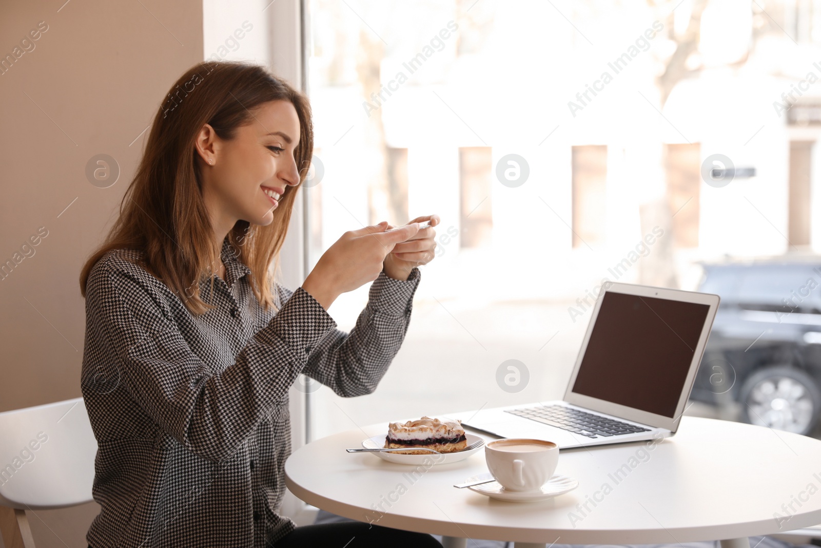 Photo of Young blogger taking photo of dessert in cafe