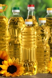 Bottles of cooking oil and sunflowers on wooden table