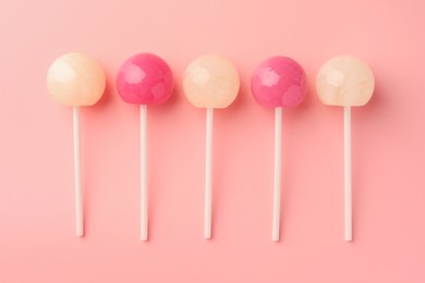 Tasty lollipops on pink background, flat lay