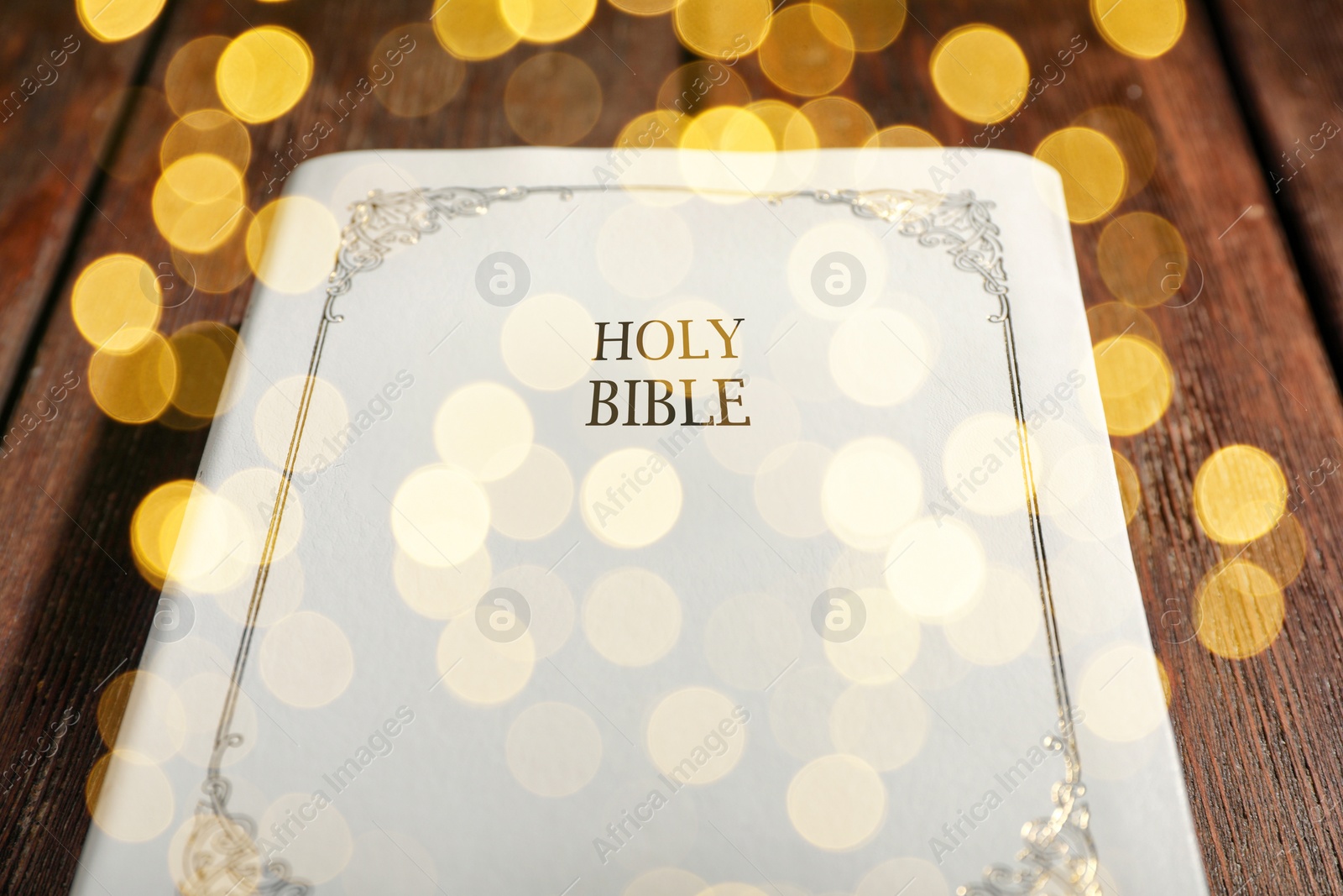 Image of Holy Bible on wooden table, bokeh effect