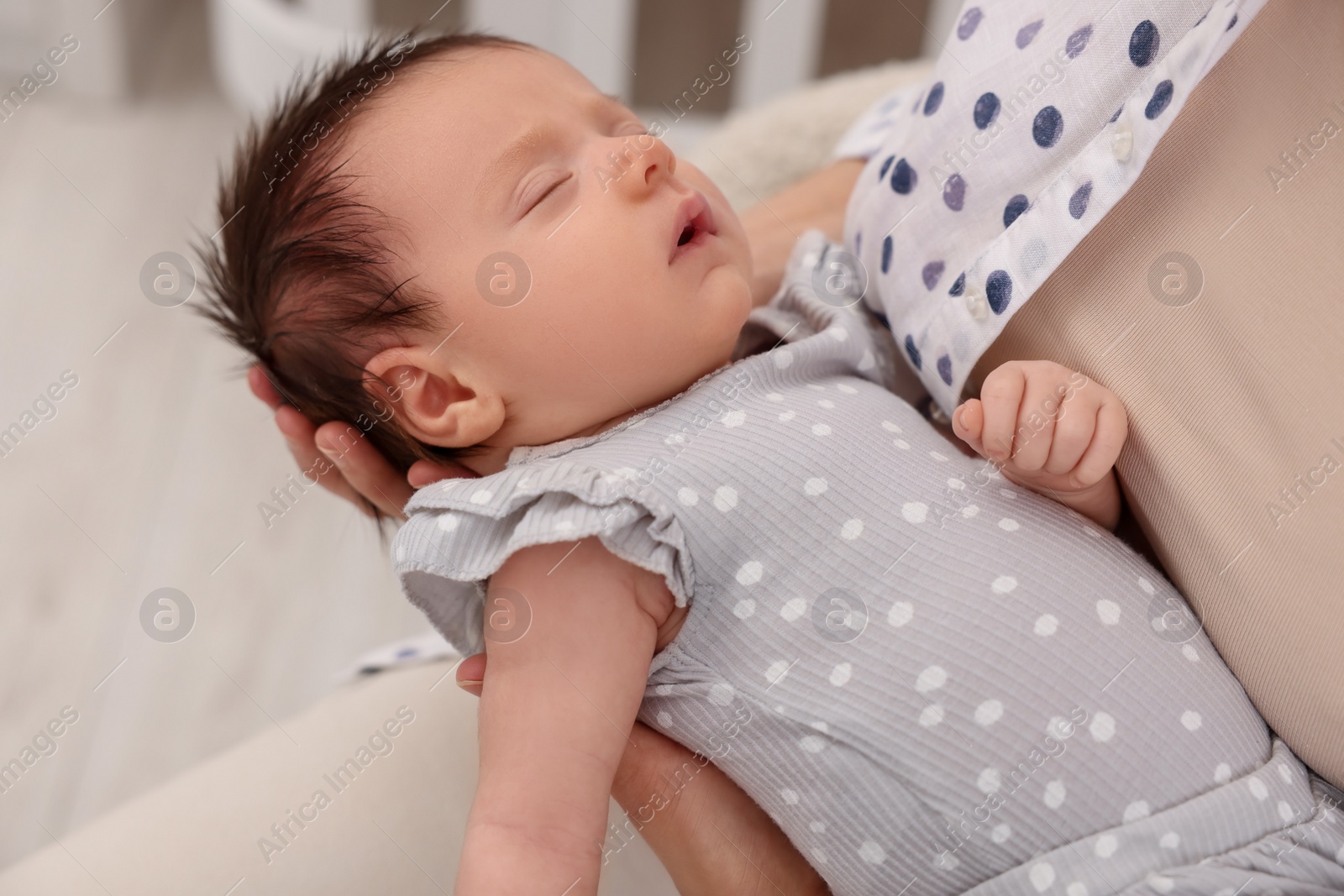 Photo of Mother with her sleeping newborn baby on blurred background, closeup