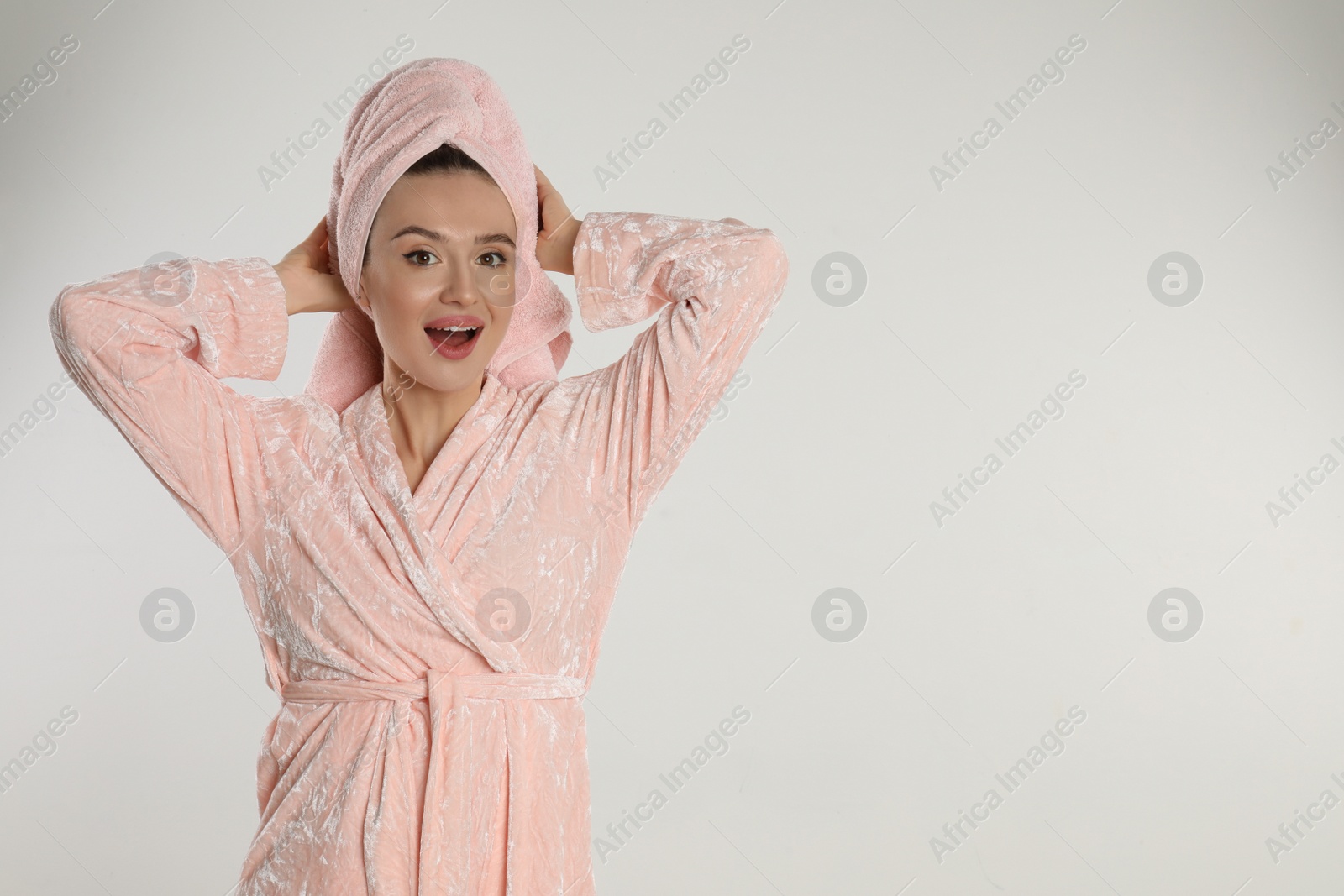 Photo of Beautiful young woman in bathrobe on light background. Space for text