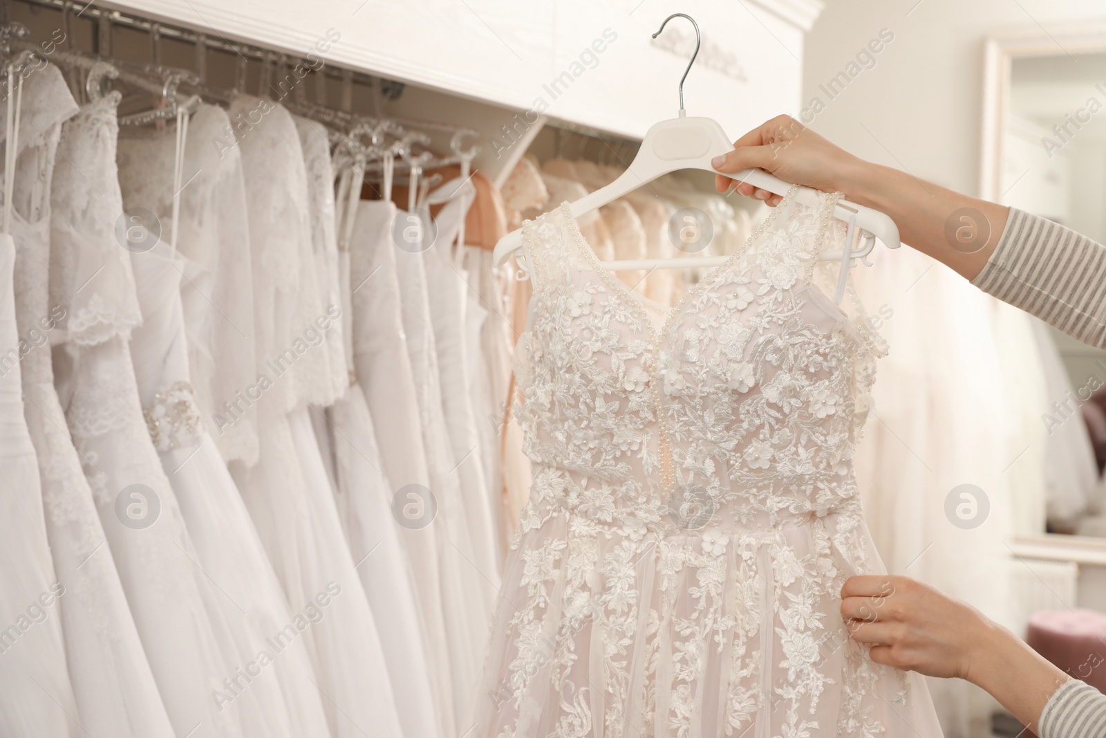 Photo of Young woman choosing wedding dress in salon, closeup