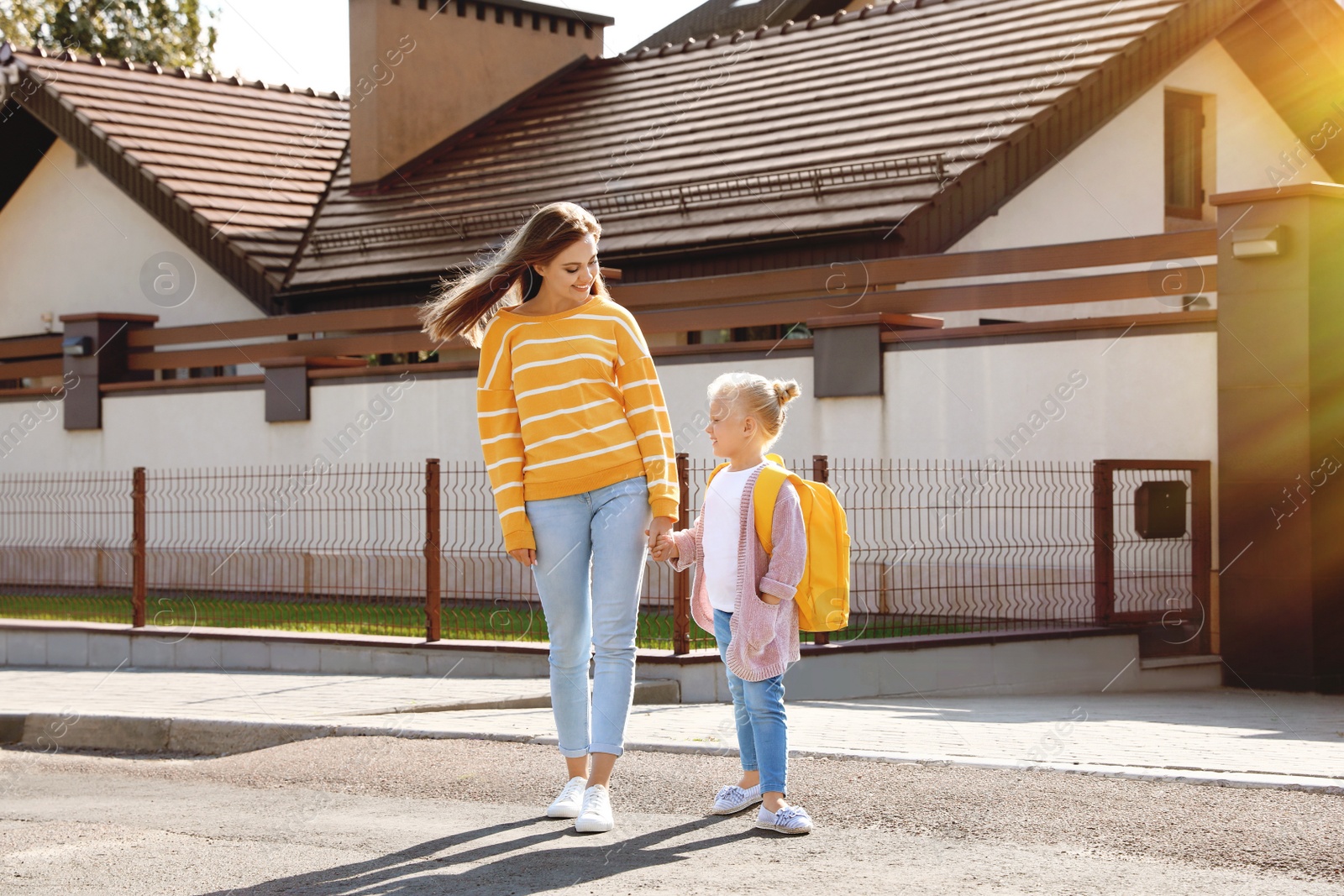 Image of Young mother taking her little child to school on street