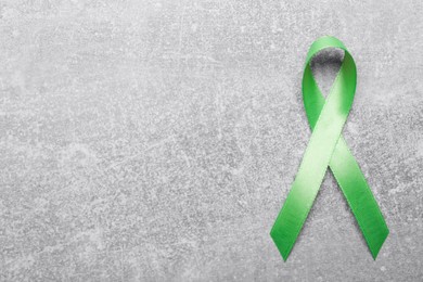 Photo of World Mental Health Day. Green ribbon on light grey background, top view with space for text