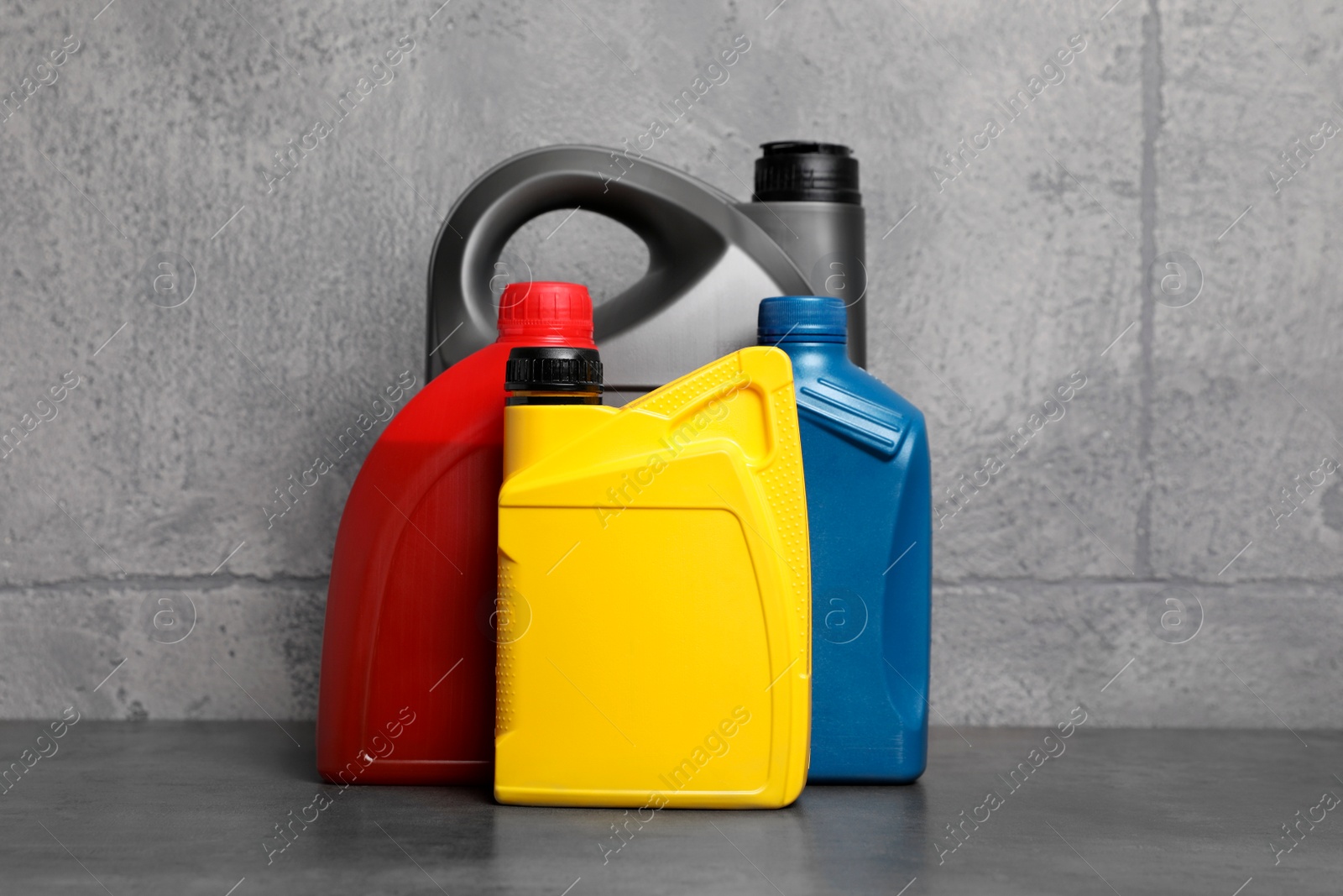 Photo of Motor oil in different canisters on table near grey wall